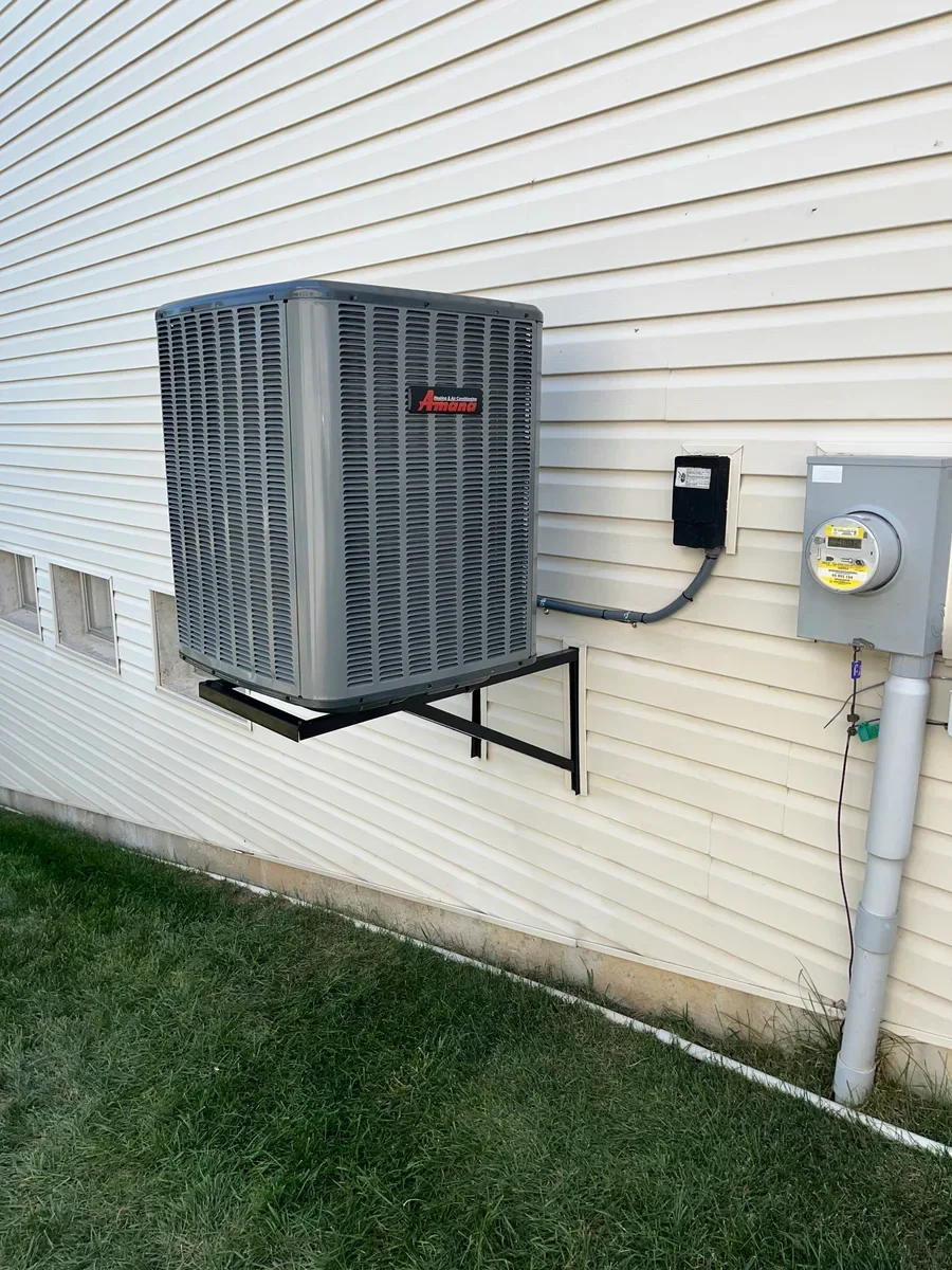 Completed wall-mounted air conditioner replacement with the same meters visible in O'Fallon.