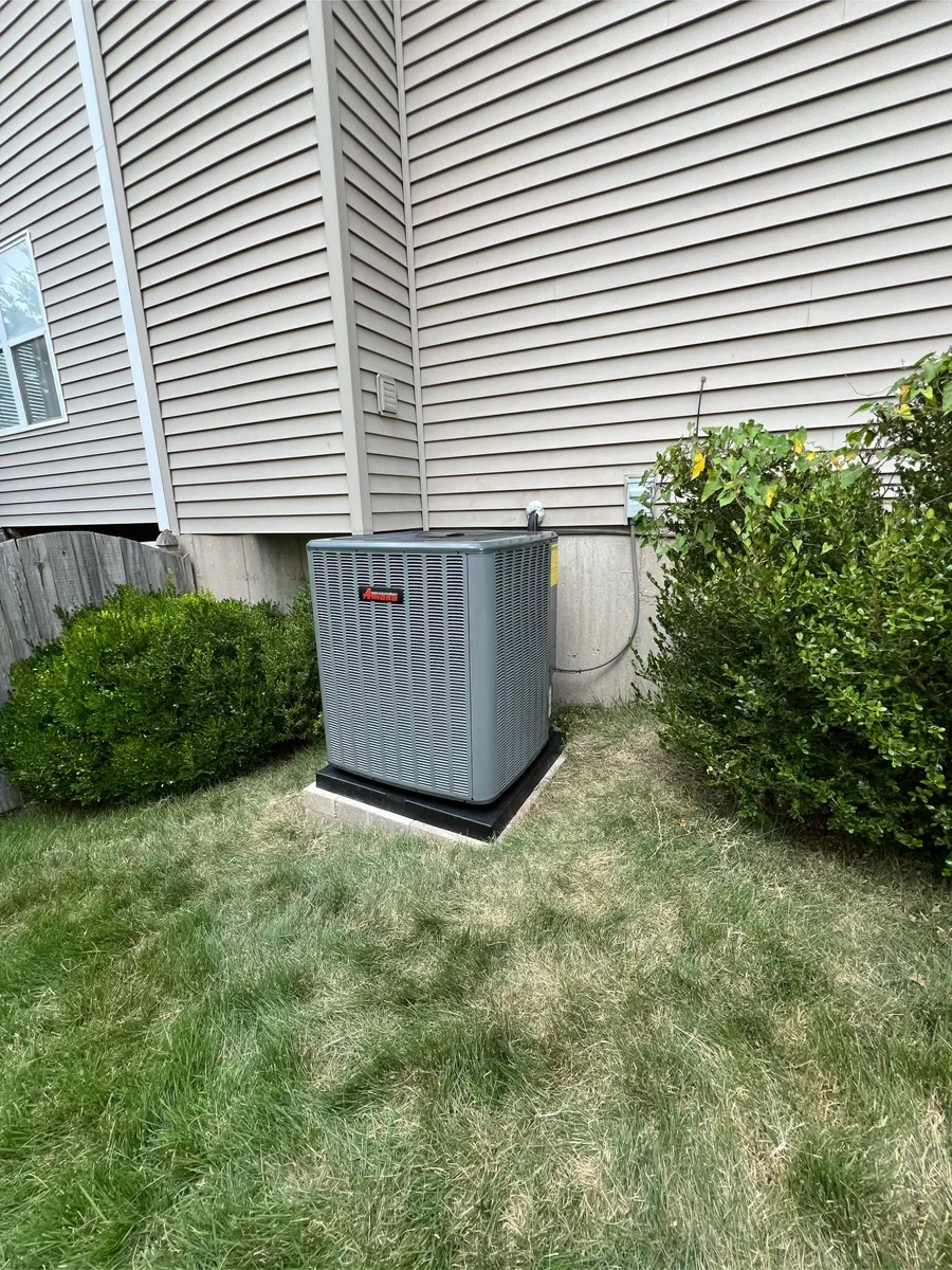 Completed air conditioner replacement between the same basement window and shrubs in St. Peters.